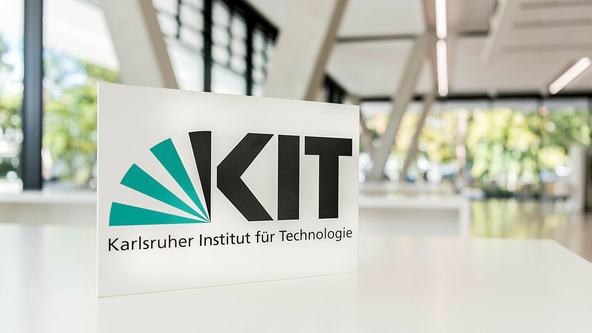 Logo des Karlsruher Instituts für Technologie (KIT) auf einem Informationstisch im Gebäude.